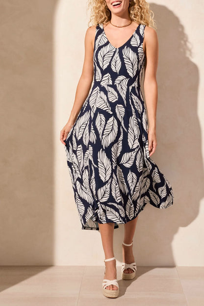 A woman stands against a light background, wearing Tribal's sleeveless high low dress featuring an abstract black and white print, paired with wedge sandals.