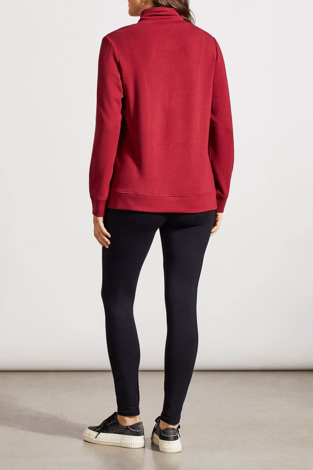 Individual dressed in a red Funnel Neck Top with Pockets by Tribal, featuring drawstrings and crafted from high-quality material, complemented by black pants.