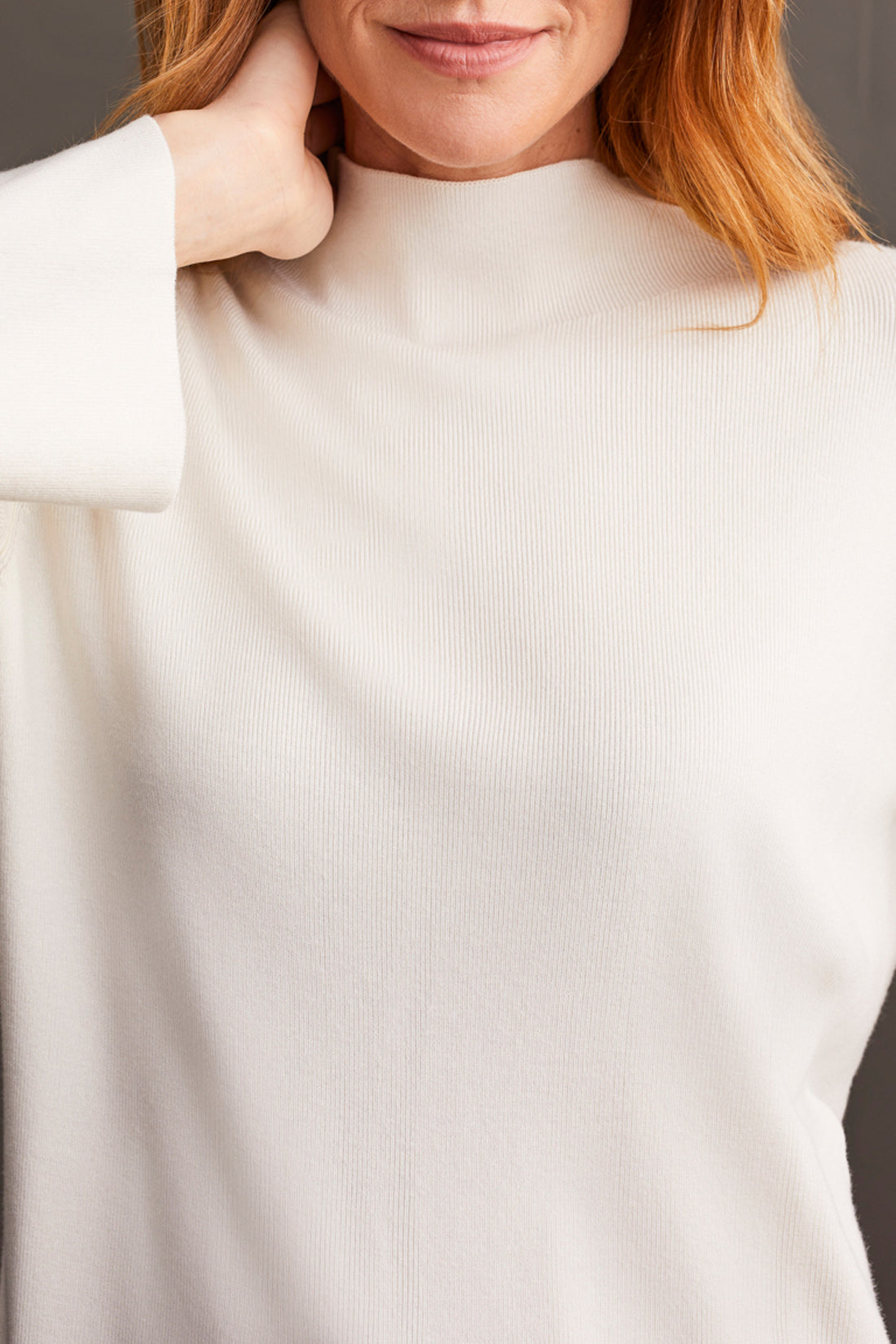 A woman with shoulder-length hair wearing a cozy and stylish yellow Funnel Neck Sweater from Tribal crosses her arms.