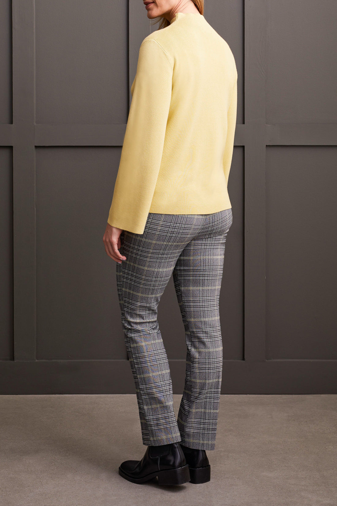 A woman with shoulder-length hair wearing a cozy and stylish yellow Funnel Neck Sweater from Tribal crosses her arms.