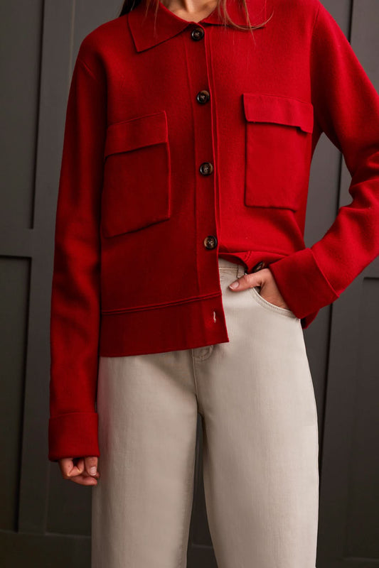 A person wearing the Tribal Sweater Cardigan with Collar and light-colored pants, standing against a dark paneled background, evokes the cozy allure of ultimate comfort.