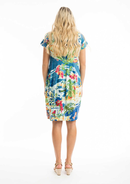A woman wears the Orientique Easy Fit Short Summer Dress with a vibrant multicolored pattern, a flattering v neckline, and beige heeled sandals against a white background.