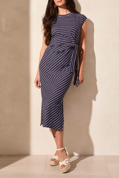 A woman stands on a tiled floor wearing Tribal's must-have SHORT SLEEVE DRESS WITH BELT, paired with a small handbag.