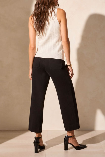 A person wearing Tribal's SWEATER VEST WITH WOOD BUTTONS and black wide-leg pants, paired with black heels, stands indoors against a neutral backdrop.