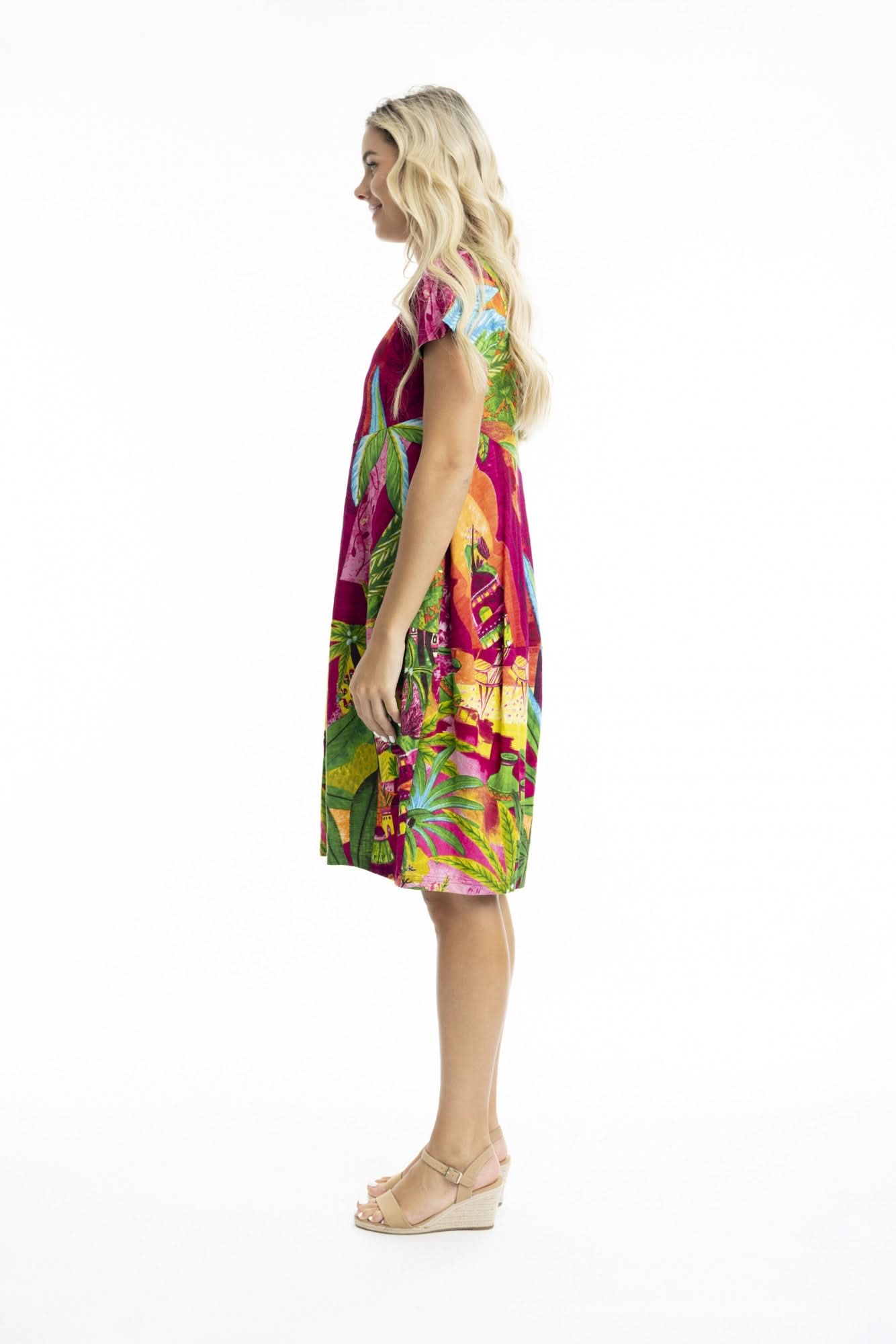 A woman poses against a white background in the Orientique Printed Cotton Short Sleeve Bubble Dress with a vibrant tropical print and beige sandals—ideal for adding playful style to your summer wardrobe.