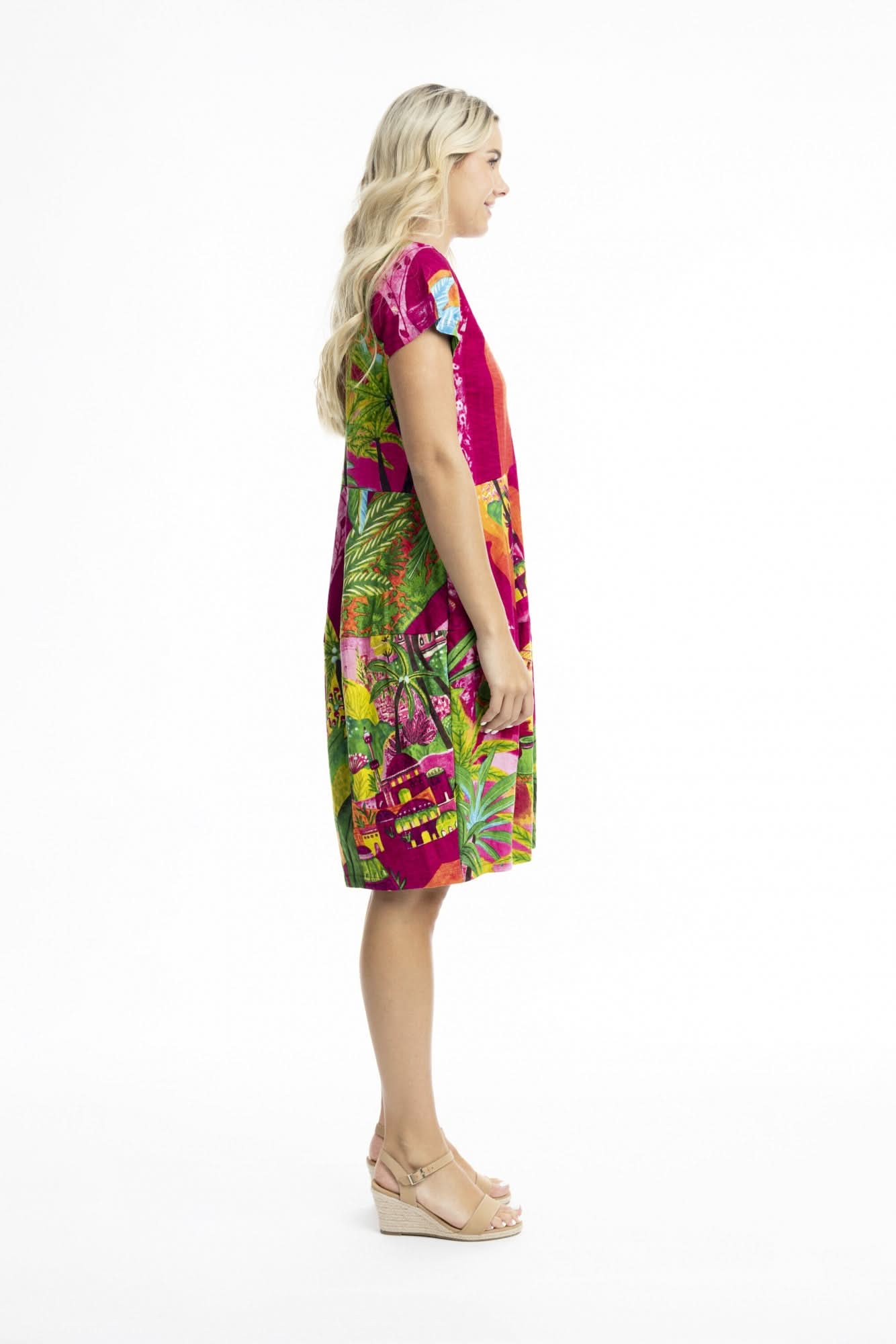 A woman poses against a white background in the Orientique Printed Cotton Short Sleeve Bubble Dress with a vibrant tropical print and beige sandals—ideal for adding playful style to your summer wardrobe.