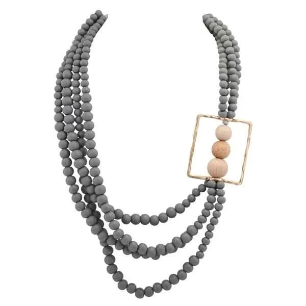 The Merx Gray/Wooden Necklace features three matte gray beaded strands and a gold rectangle pendant with three wooden beads on the right side for an elegant look.