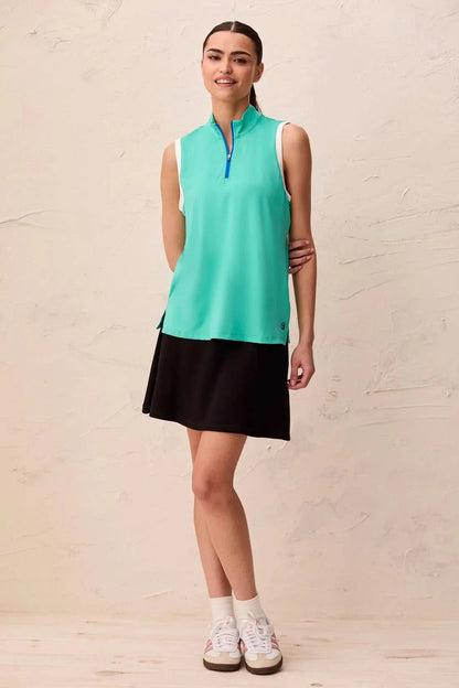 A woman models the Tribal SLEEVELESS ZIP SPORT TOP in teal, featuring a blue zippered collar and white armhole trim in lightweight scuba knit, standing indoors against a light-colored wall.