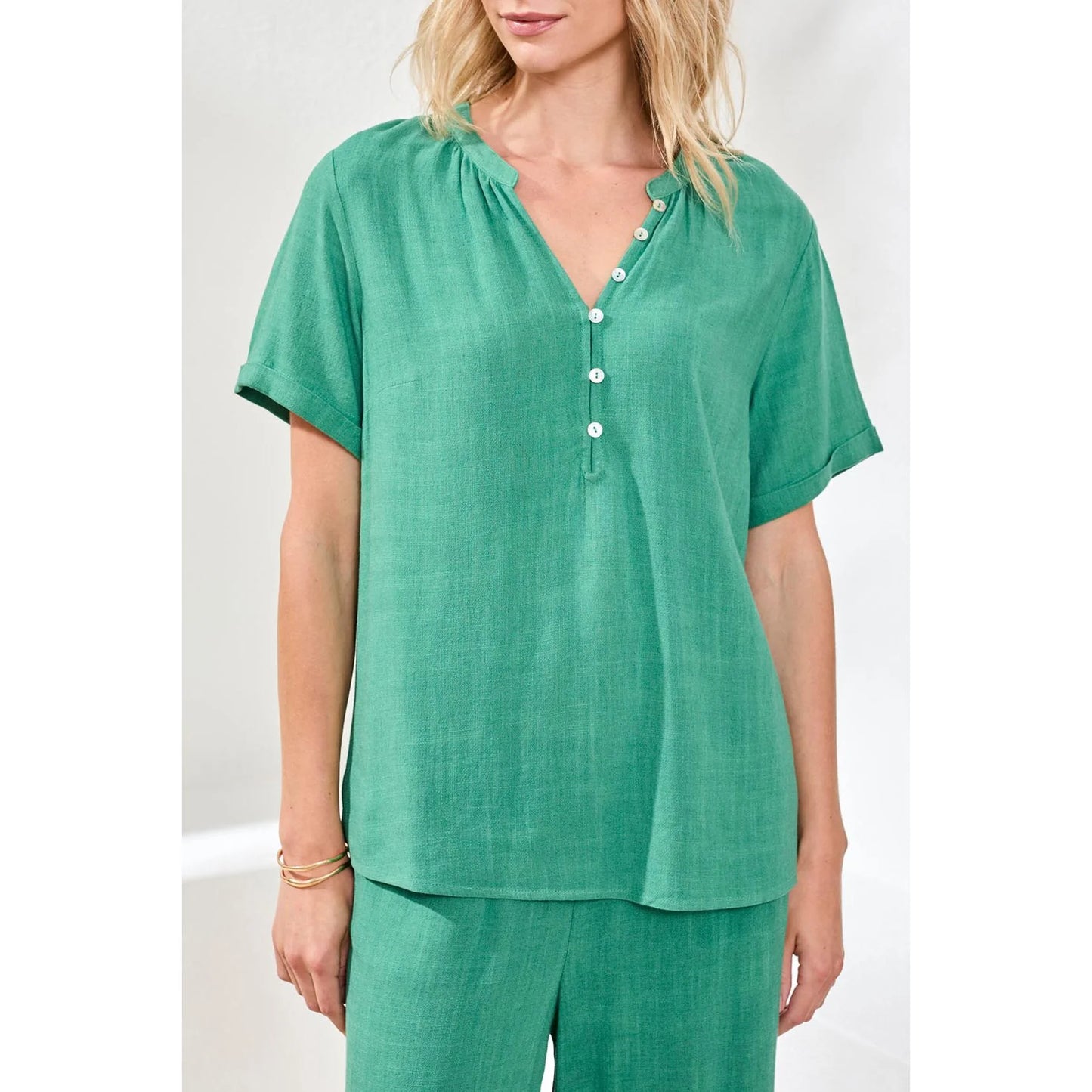 A woman wears the Tribal Coastal Pop Over Blouse, a light blue linen-rayon blend short-sleeve top, standing against a plain white background with her face partially out of frame.