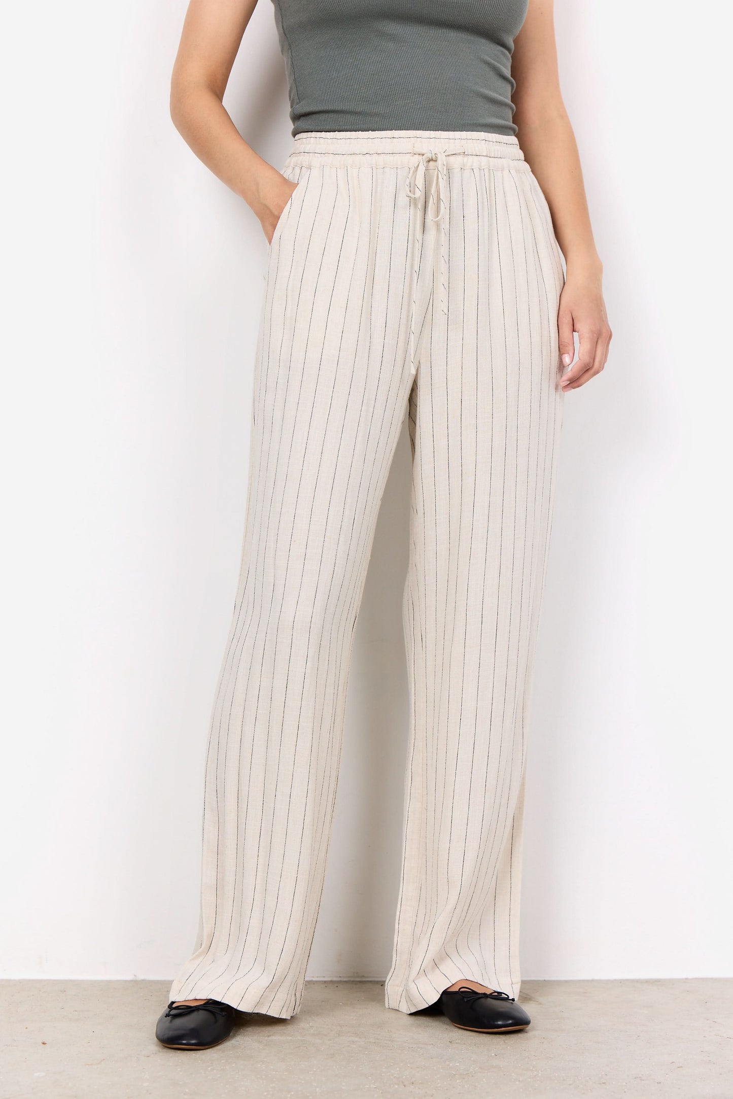 A person wearing a sleeveless gray top, Soya Concepts PAULA 2B Cream Pant, and black shoes stands against a white background.