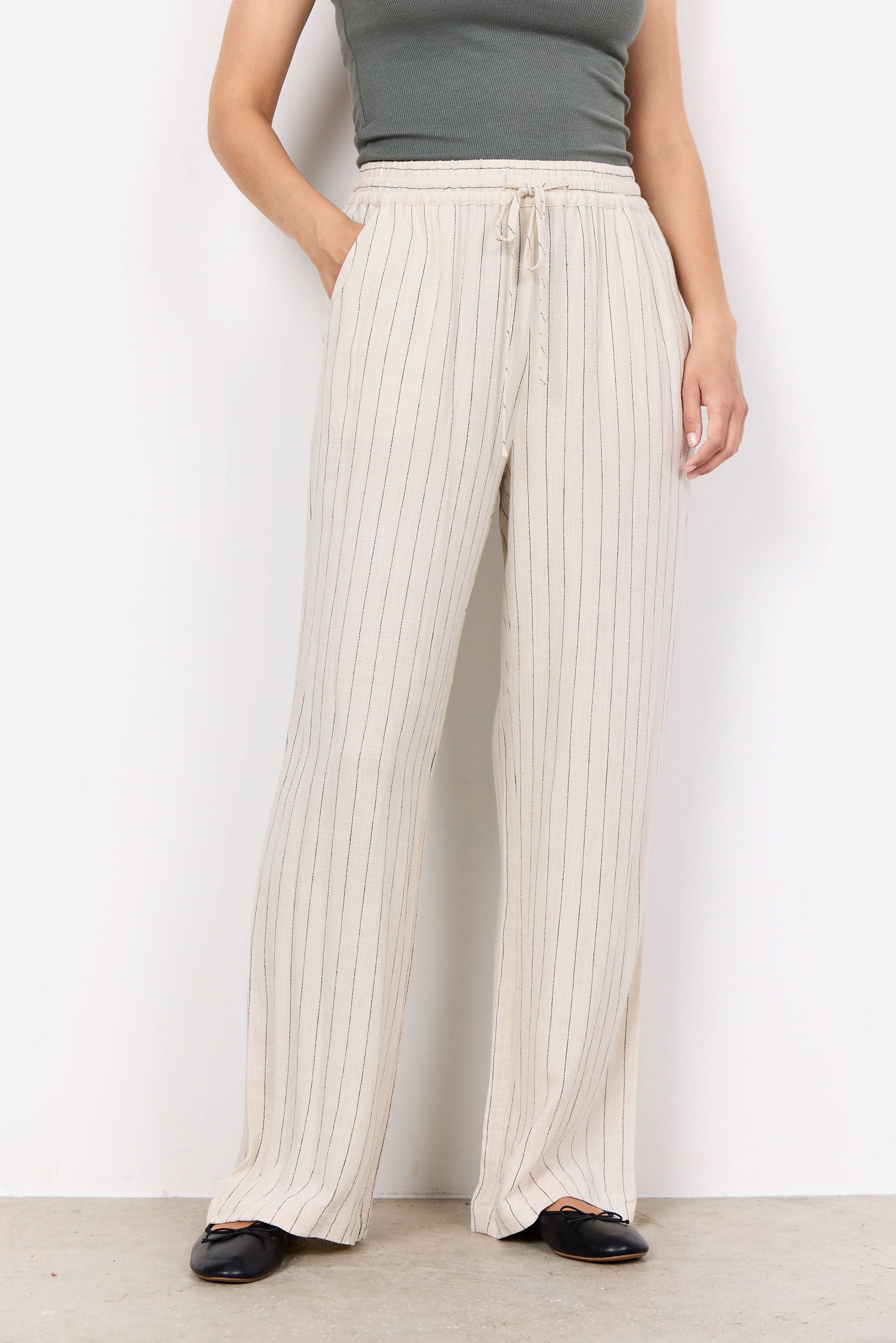 A person wearing a sleeveless gray top, Soya Concepts PAULA 2B Cream Pant, and black shoes stands against a white background.