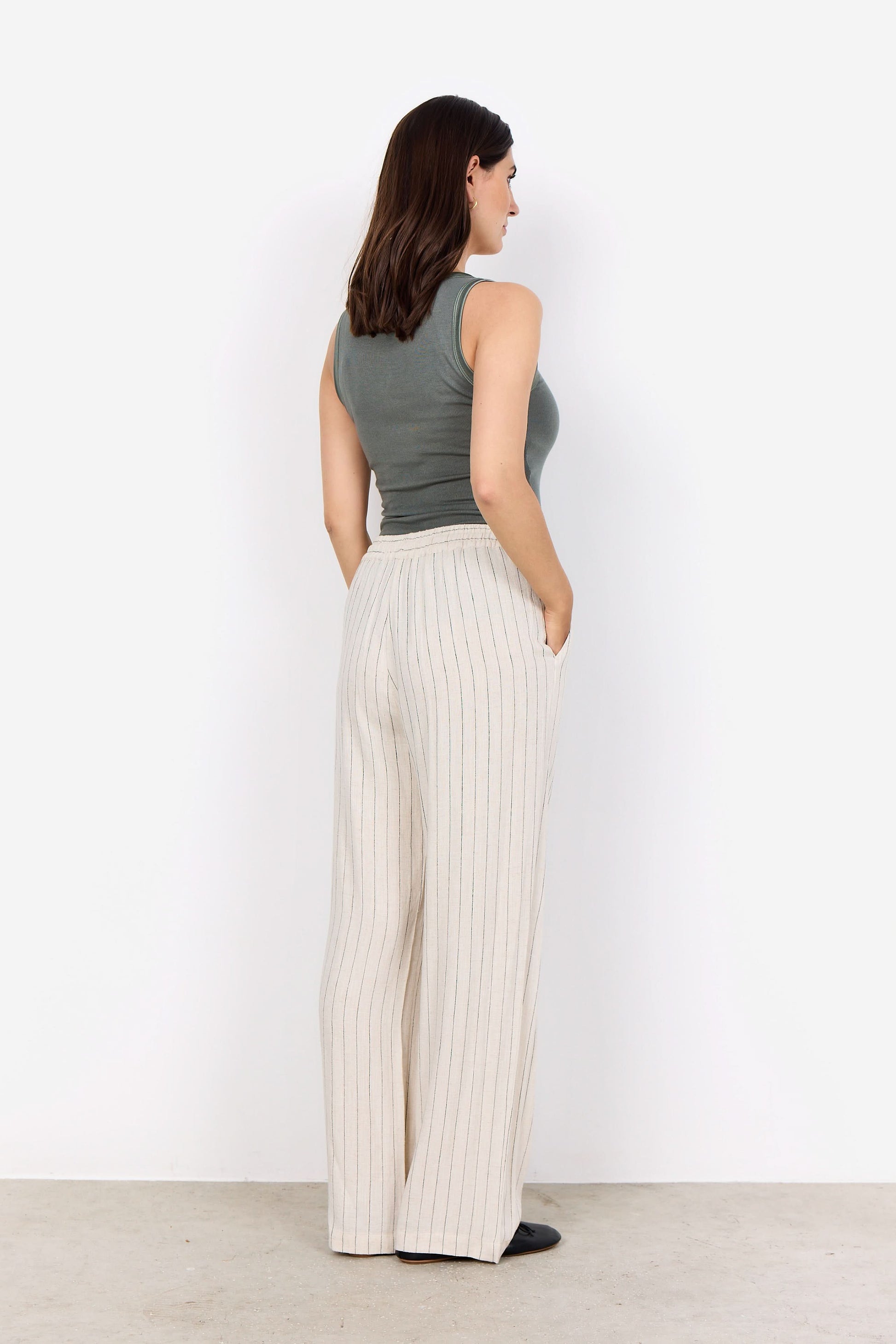 A person wearing a sleeveless gray top, Soya Concepts PAULA 2B Cream Pant, and black shoes stands against a white background.