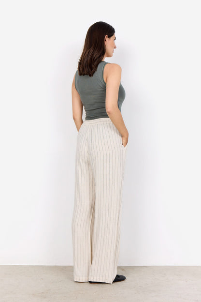 A person wearing a sleeveless gray top, Soya Concepts PAULA 2B Cream Pant, and black shoes stands against a white background.