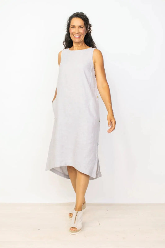 Woman smiling and posing in a Habitat Side Button Detail Sleeveless Dress in gray against a white background.