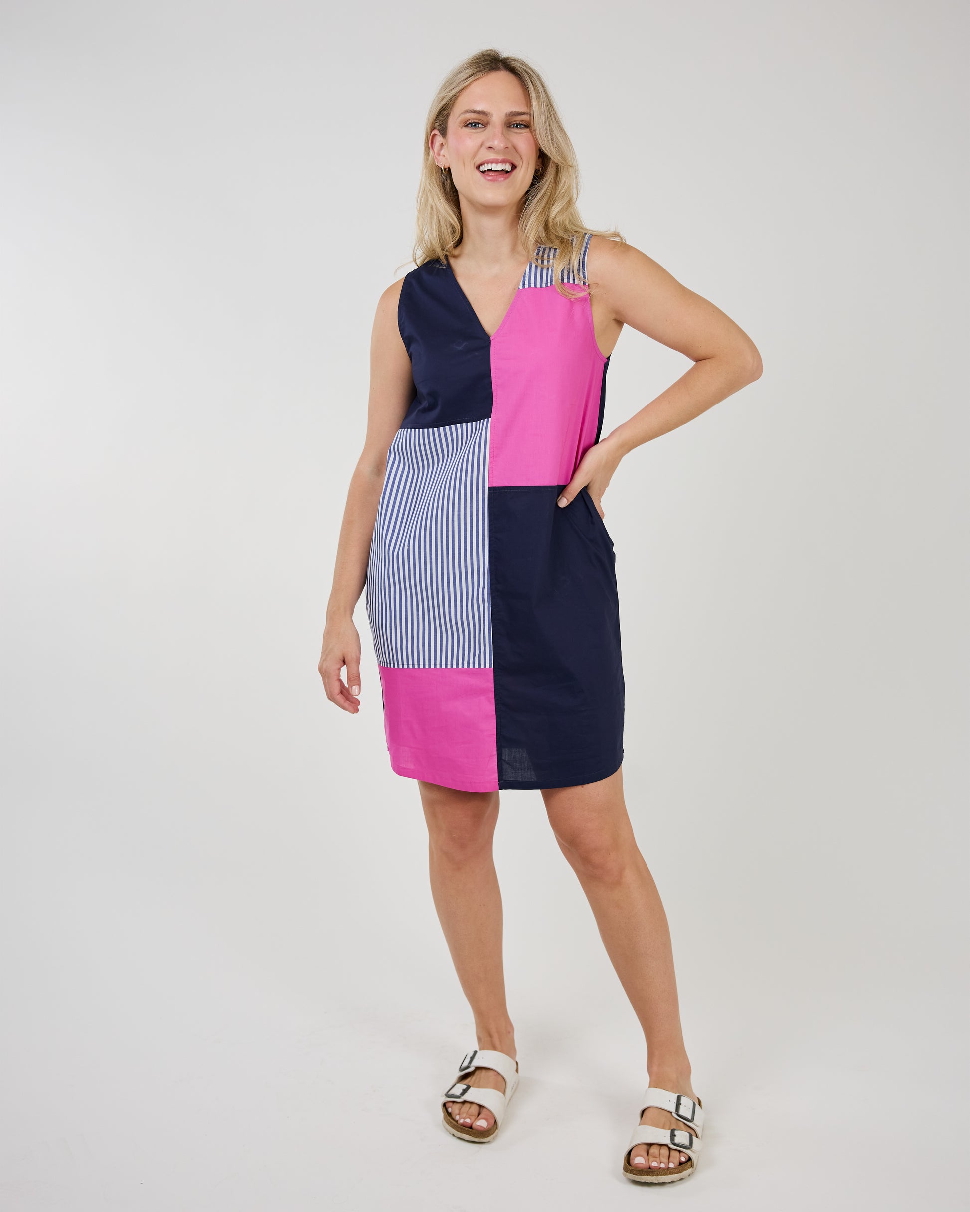 A woman wearing a Shannon Passero Multi Patch Tank Dress with colorful patches and stripes standing against a white background.