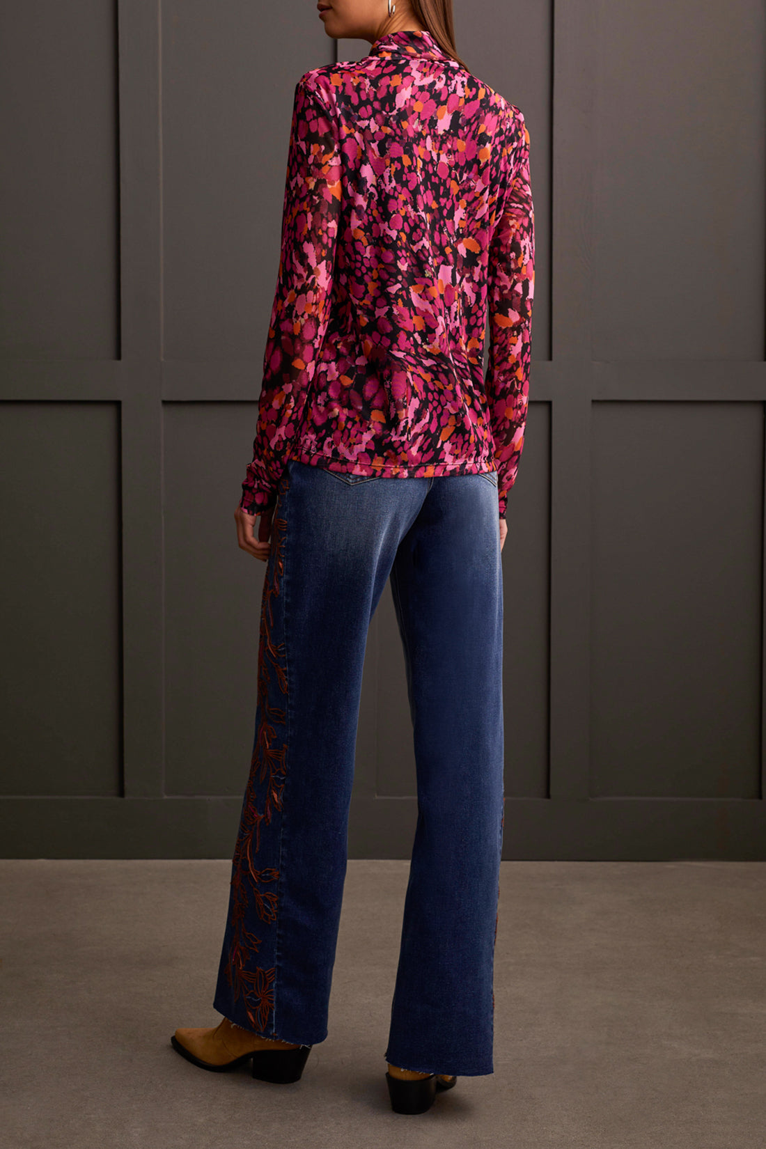 A person wearing a cozy Tribal Turtleneck Lined Top and high-waisted wide-leg jeans stands in front of a paneled wall. Brown shoes are visible at the bottom of the jeans, completing this perfect winter wardrobe look.