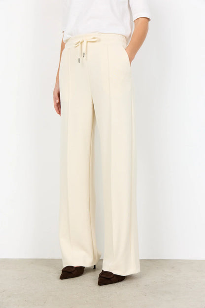 Wearing the Soya Concepts Banu Long Sleeve Sweater in off-white, paired with matching pants, this individual showcases relaxed style and all-day comfort against a simple backdrop.