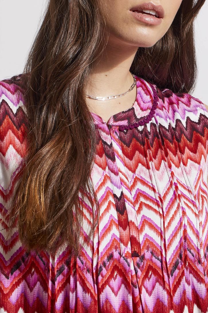Woman wearing a trendy sleeveless Tribal top with a pink and white zigzag pattern.