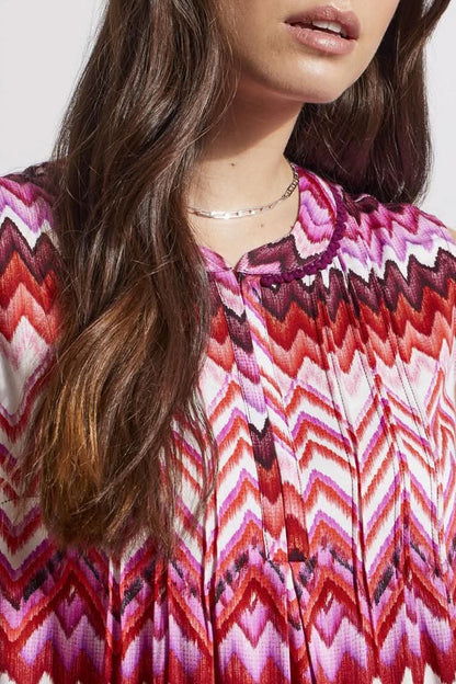 Woman wearing a trendy sleeveless Tribal top with a pink and white zigzag pattern.