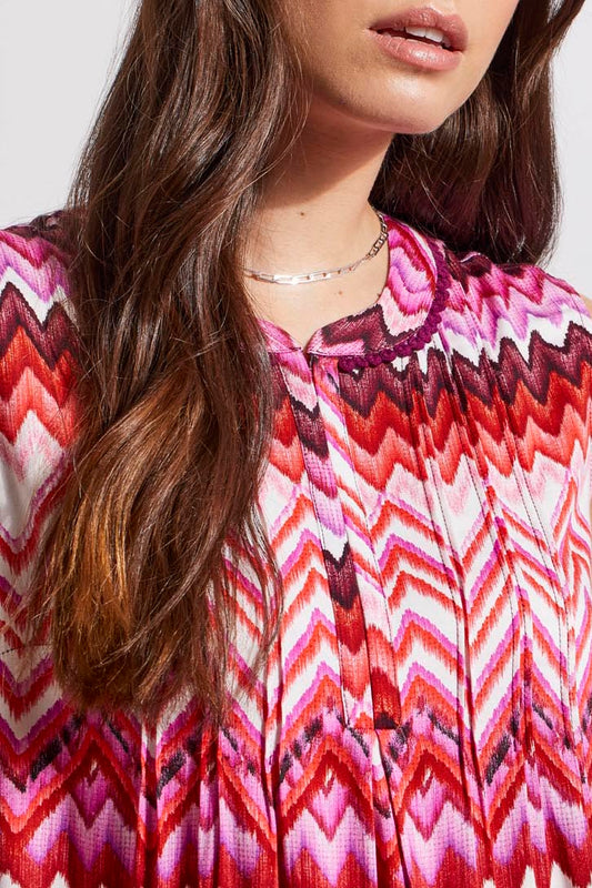 Woman wearing a trendy sleeveless Tribal top with a pink and white zigzag pattern.