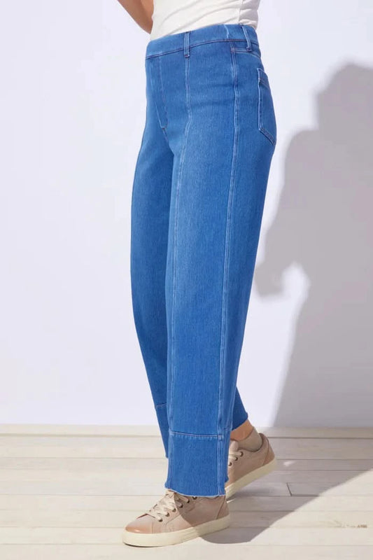 A person wears Escape’s Comfort Knit Denim Jean—high-waisted, wide-leg, and soft for everyday comfort—with beige sneakers, standing on a light floor against a white background.