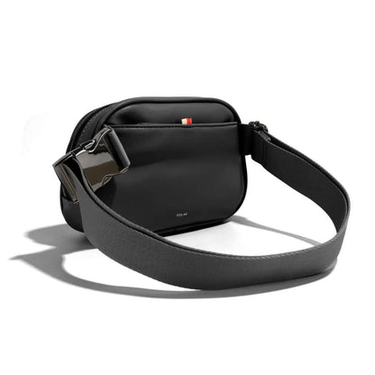 The Co-Lab Neoma sling bag features a small, rounded shape, teal vegan leather with a ribbed texture, and a wide black shoulder strap.