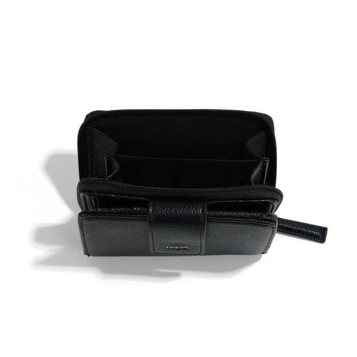 A person in a light gray shirt and beige pants holds The Lucie Small Wallet by Co-Lab, an eco-friendly, compact green wallet with both zipper and snap closures.