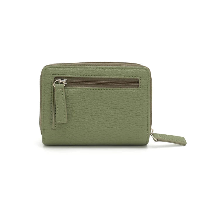 A person in a light gray shirt and beige pants holds The Lucie Small Wallet by Co-Lab, an eco-friendly, compact green wallet with both zipper and snap closures.