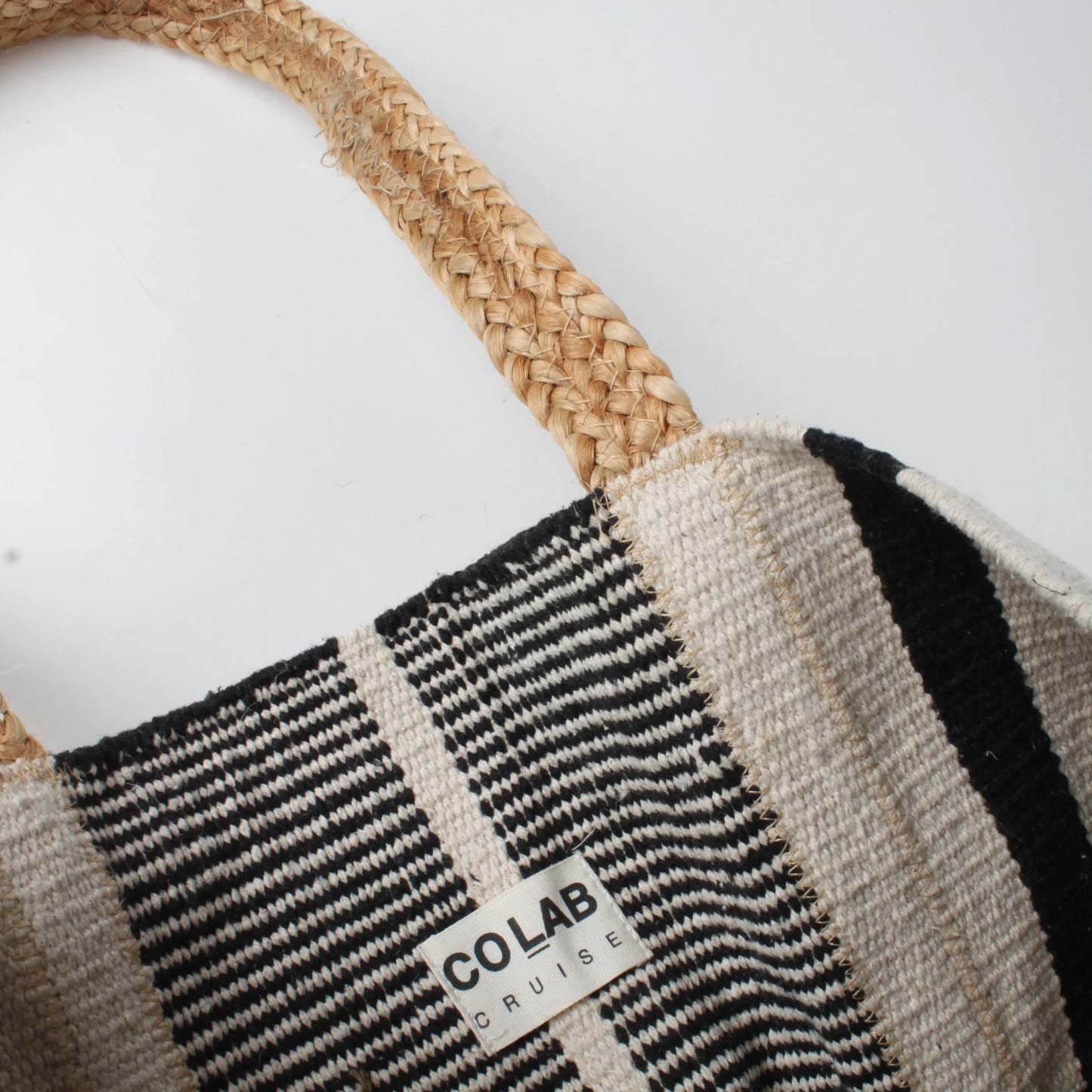 Close-up of the Co-Lab Santa Barbara Stripe Beach Tote, featuring thick braided straw handles and a black and white striped body—a stylish accessory for beach outings.