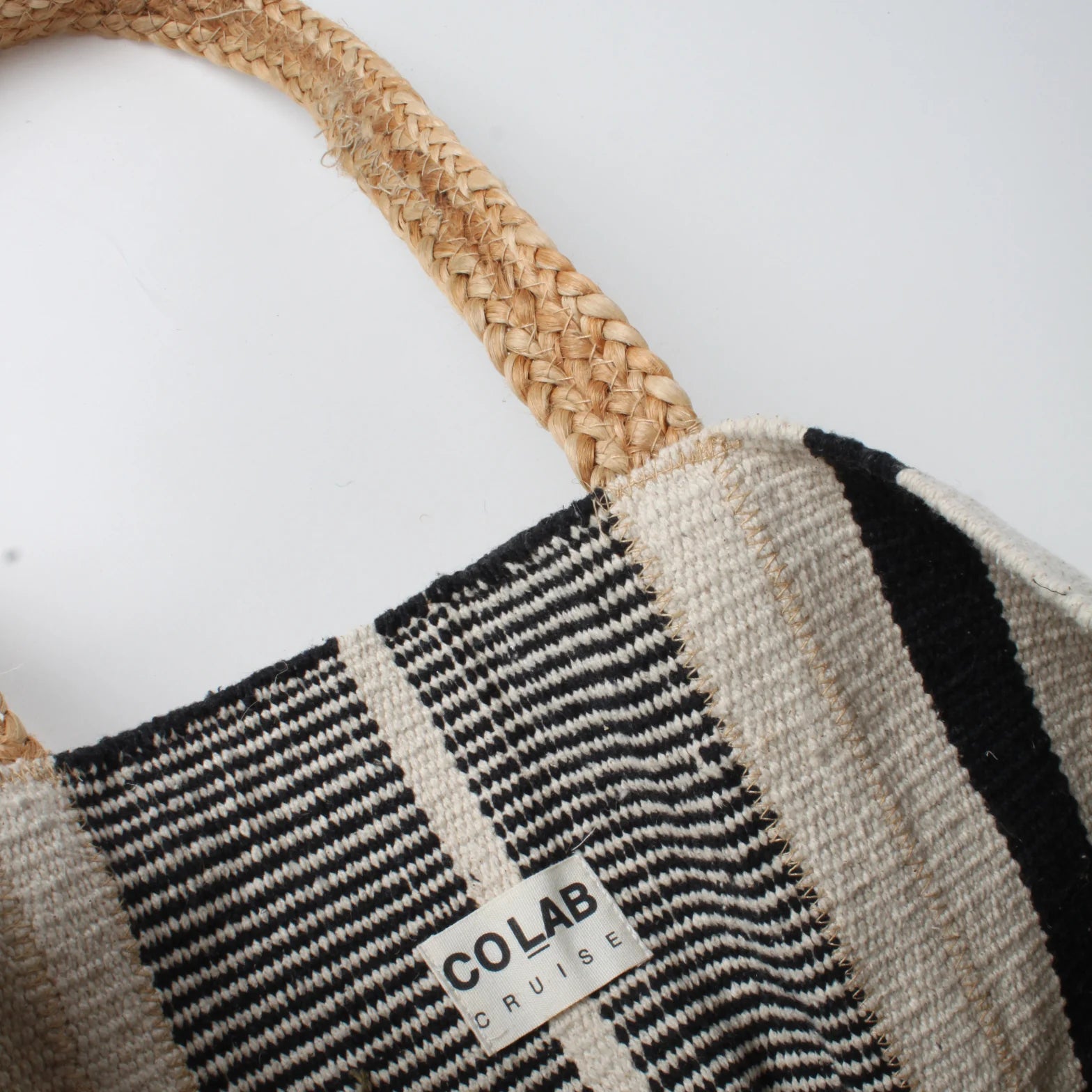 Close-up of the Co-Lab Santa Barbara Stripe Beach Tote, featuring thick braided straw handles and a black and white striped body—a stylish accessory for beach outings.