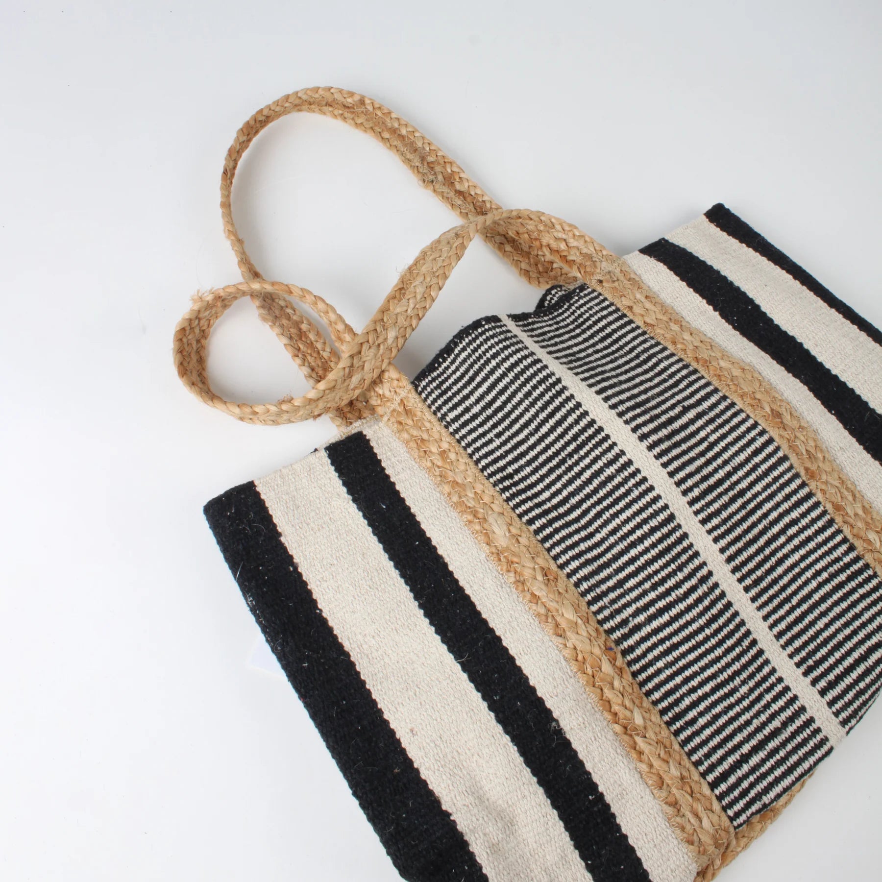 Close-up of the Co-Lab Santa Barbara Stripe Beach Tote, featuring thick braided straw handles and a black and white striped body—a stylish accessory for beach outings.