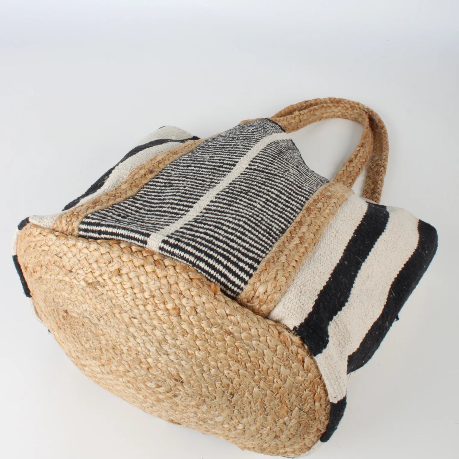 Close-up of the Co-Lab Santa Barbara Stripe Beach Tote, featuring thick braided straw handles and a black and white striped body—a stylish accessory for beach outings.