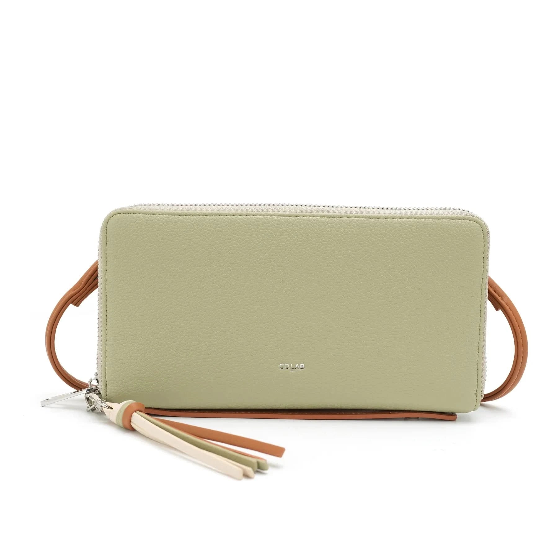 A woman in a light gray button-up shirt and beige pants holds Co-Lab’s sustainable 'ALEXX' Wallet in light green near her chest.