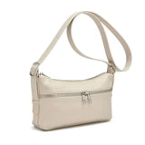 A woman in a sleeveless brown top and matching pants stands against a plain background, holding the Co-Lab THE 'MILA' SHOULDER BAG / CROSSBODY.