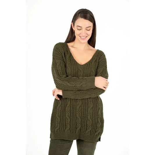 Dressed in an M Made In Italy Cable Knit Oversized V Neck Sweater paired with pants, a person stands with their arms crossed and a subtle smile against a plain white backdrop.