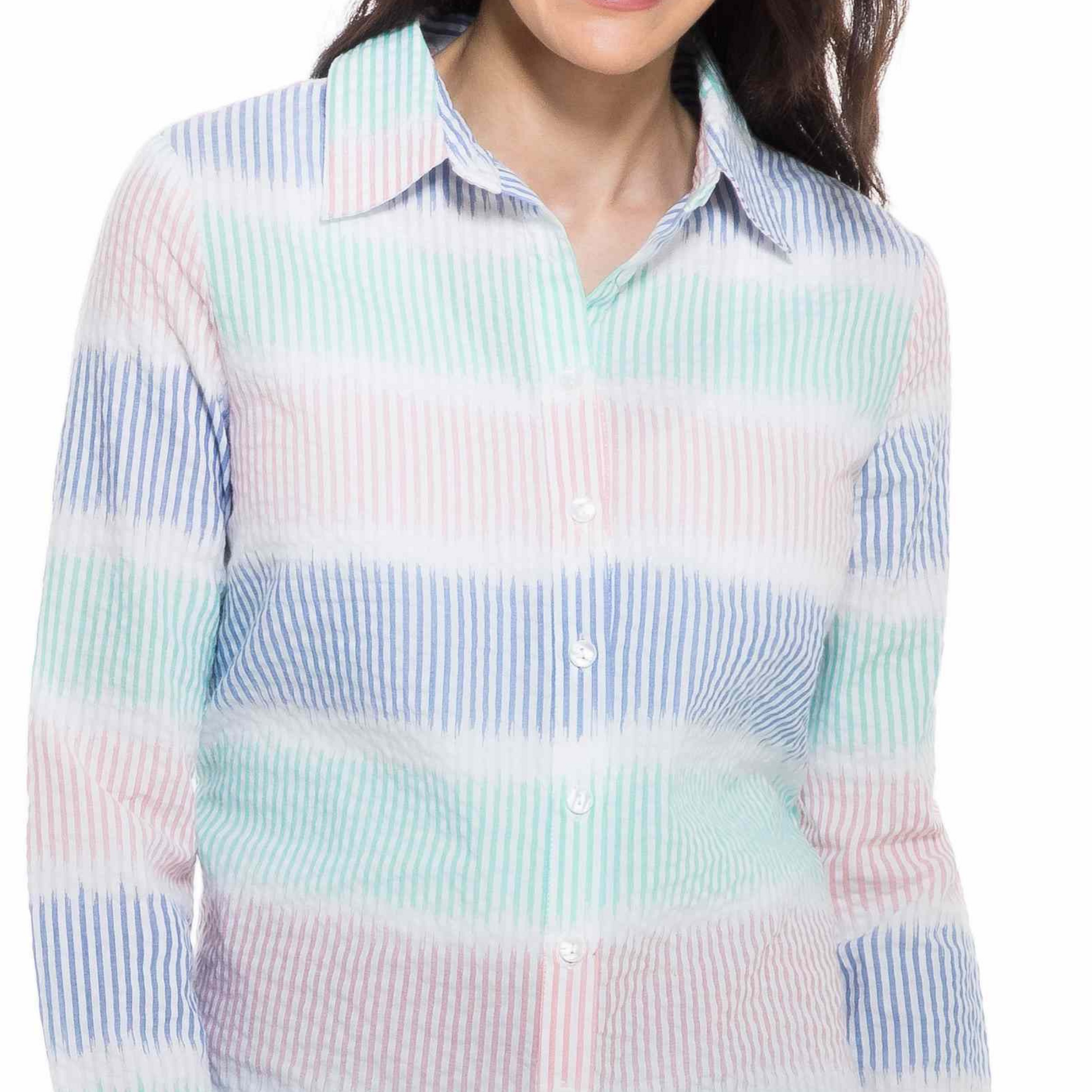 A fashionista smiling at the camera, wearing a Orly Blue Combo Striped Shirt and blue jeans, standing against a white background.