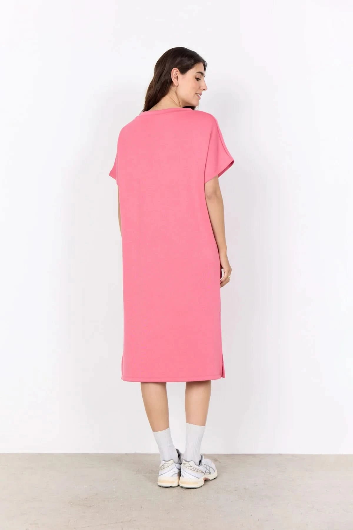 A woman stands against a white background wearing the Soya Concepts Banu V Neck Dress—a loose-fitting, knee-length pink dress with short sleeves.