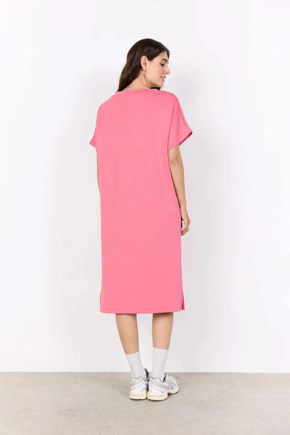 A woman stands against a white background wearing the Soya Concepts Banu V Neck Dress—a loose-fitting, knee-length pink dress with short sleeves.