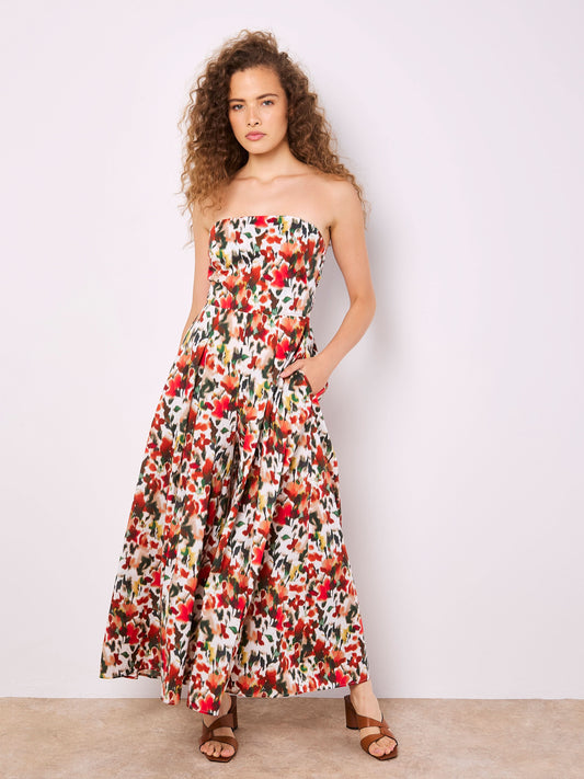 A person with curly hair wearing Apricot's Blurred Floral Palazzo Jumper stands in sandals against a plain background.