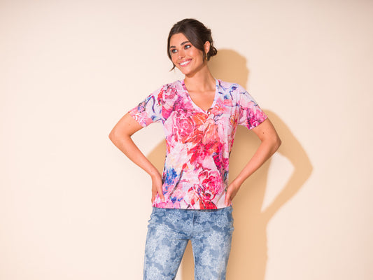 A woman in a soft and comfortable Alison Sheri V Neck Pink Floral Tee and jeans posing for a photo.