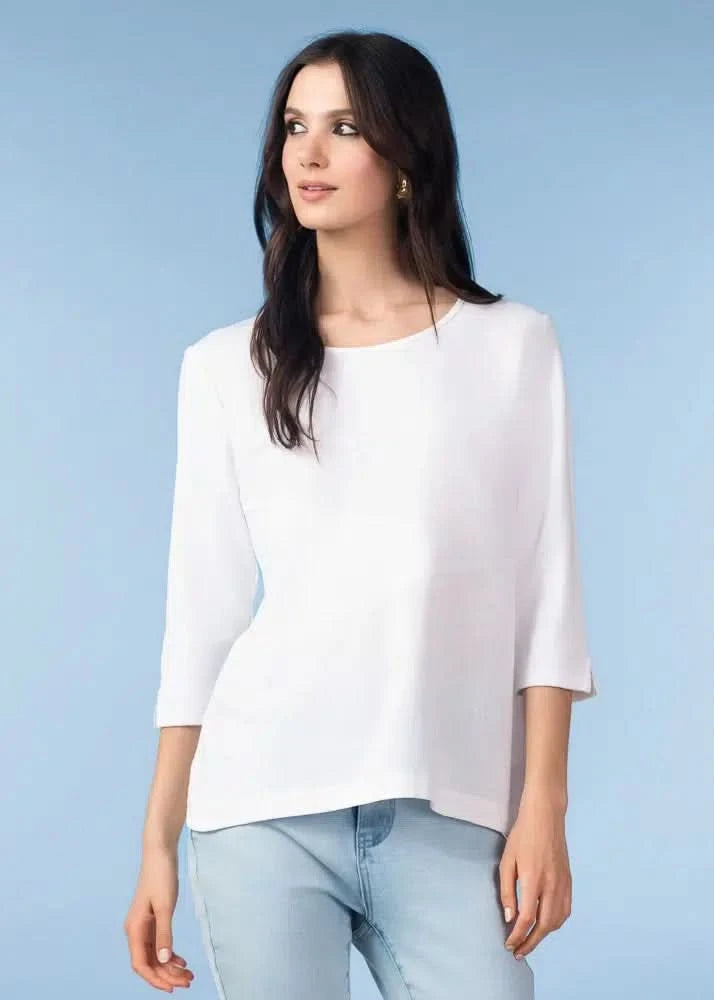 A woman models the Alison Sheri Floaty top with light blue jeans against a plain light blue background, creating a polished everyday look.
