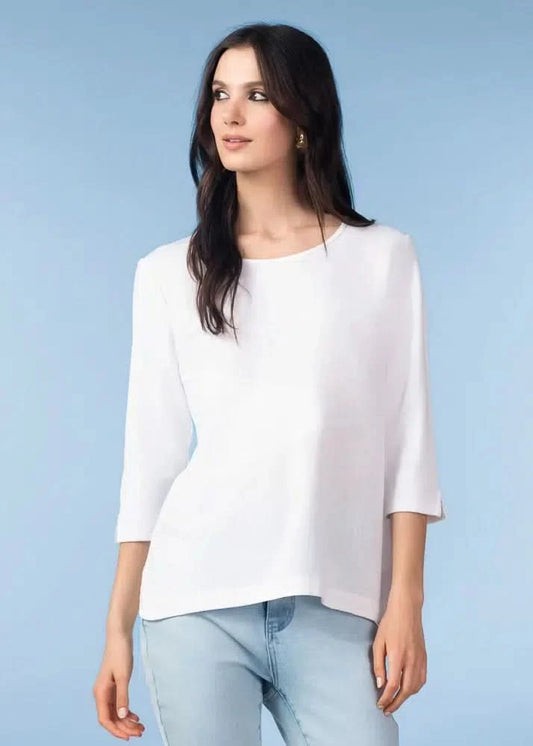 A woman models the Alison Sheri Floaty top with light blue jeans against a plain light blue background, creating a polished everyday look.