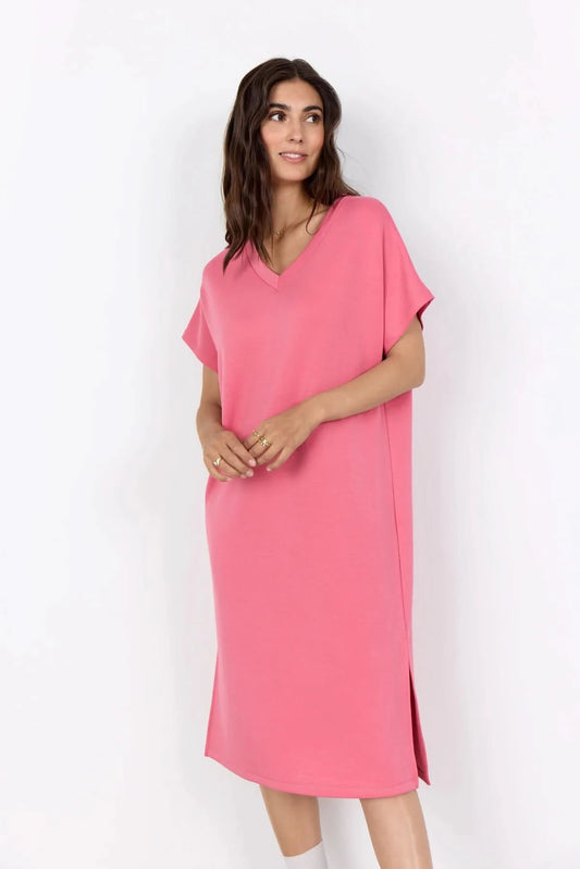 A woman stands against a white background wearing the Soya Concepts Banu V Neck Dress—a loose-fitting, knee-length pink dress with short sleeves.