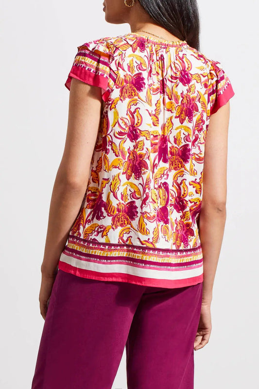 Woman wearing a Tribal Border Print Blouse with Frill and purple pants.