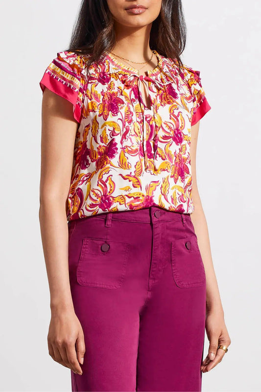 Woman wearing a Tribal Border Print Blouse with Frill and purple pants.