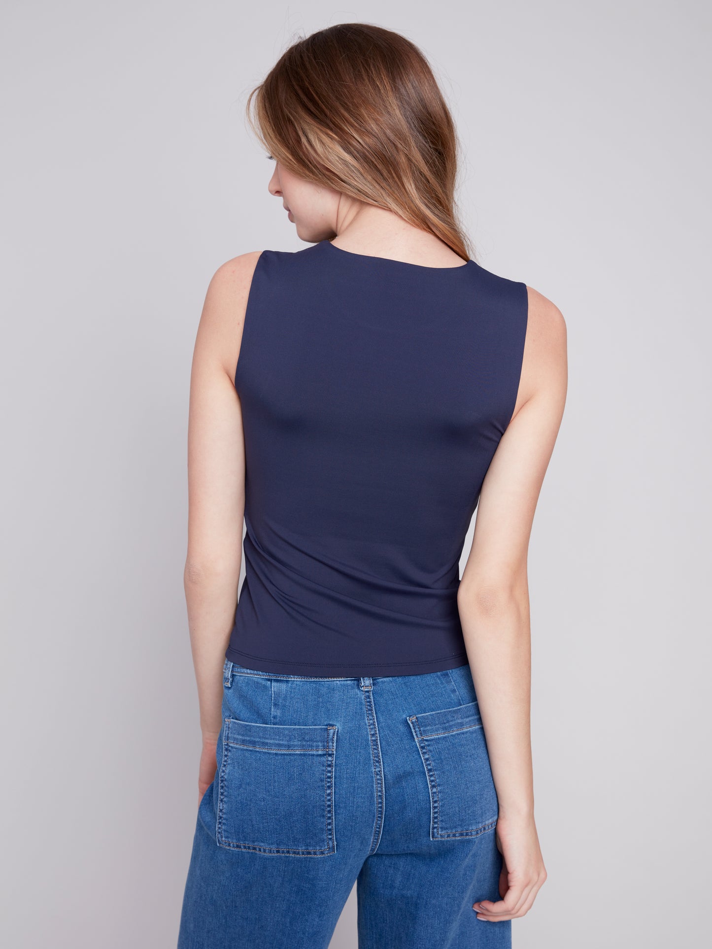 The fashionable model is wearing a comfortable Charlie B navy Sleeveless Rib Tank Top and blue jeans.