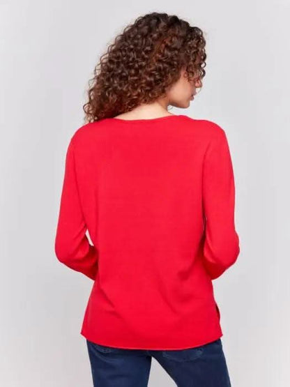 A person in a red Basic V Neck Long Sleeve Sweater by Charlie B and blue jeans stands against a plain background.