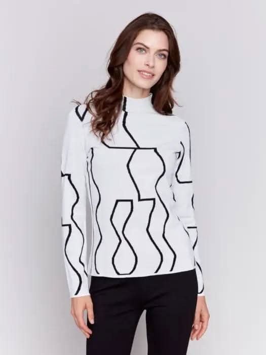 A person wearing the Reversible Jacquard Mock Neck Sweater by Charlie B, featuring black abstract patterns, stands with their back to the camera, showcasing an essential piece for any winter wardrobe.