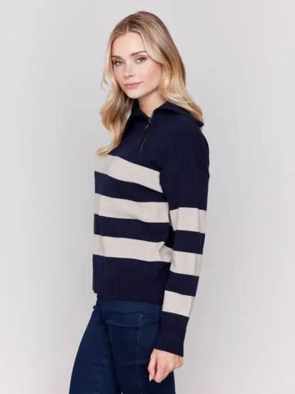 A person with light-colored hair wears a high-quality Charlie B Striped Turtleneck with Side Zip in navy and white, paired with dark pants against a plain background.
