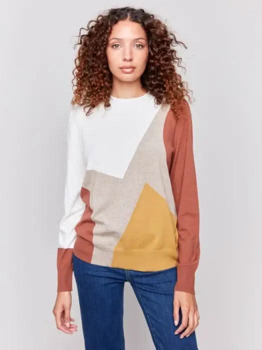 A person with curly hair is wearing the cozy and stylish Charlie B Ecru Colorblock Long Sleeve Sweater and blue jeans, standing against a plain background.